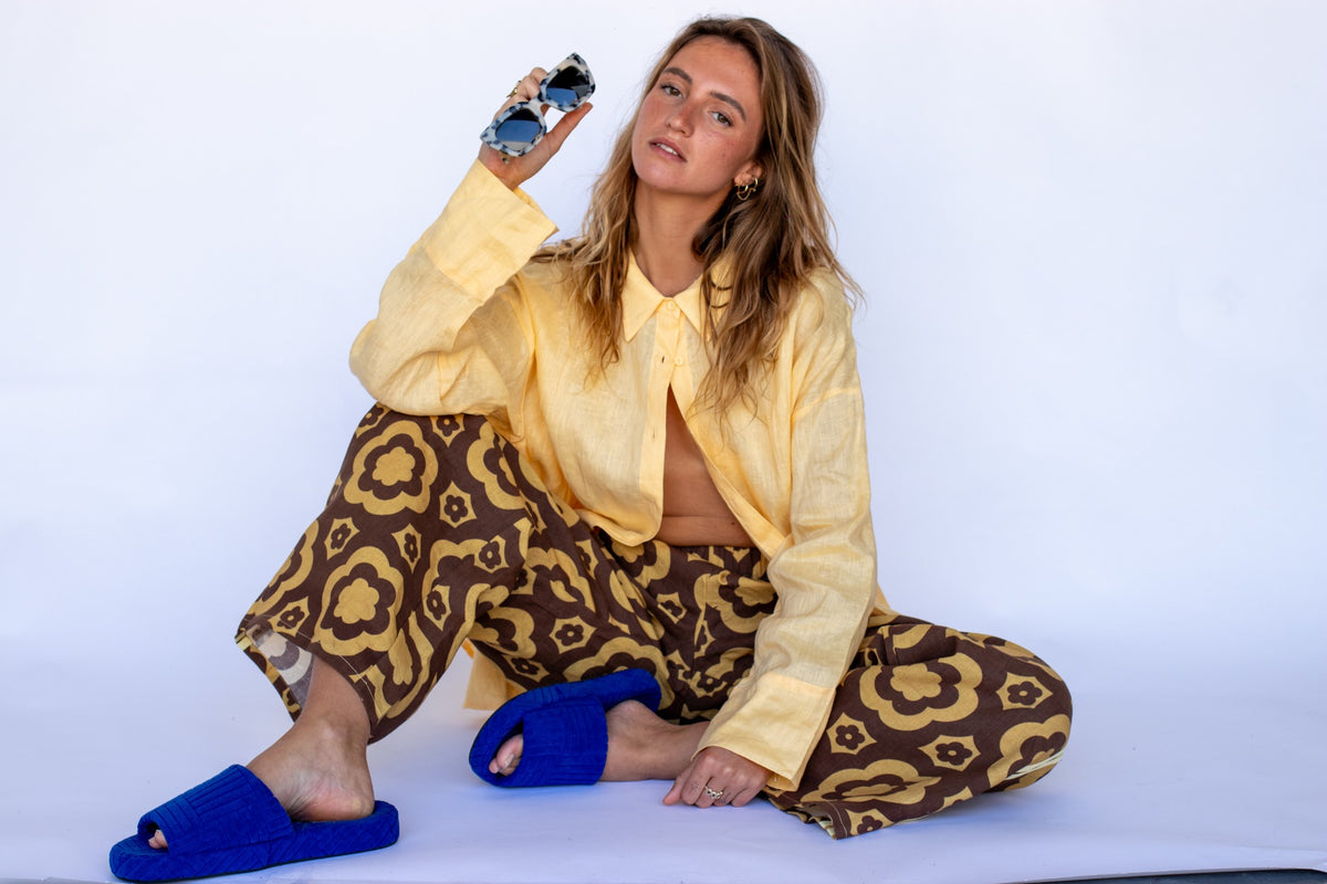Locolinen Bloomin Groover floral pants styled with a yellow linen shirt and blue sandals